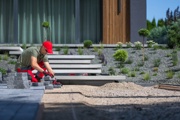 Arbeiter verlegen Steinplatten im angelegten Garten an einem sonnigen Nachmittag